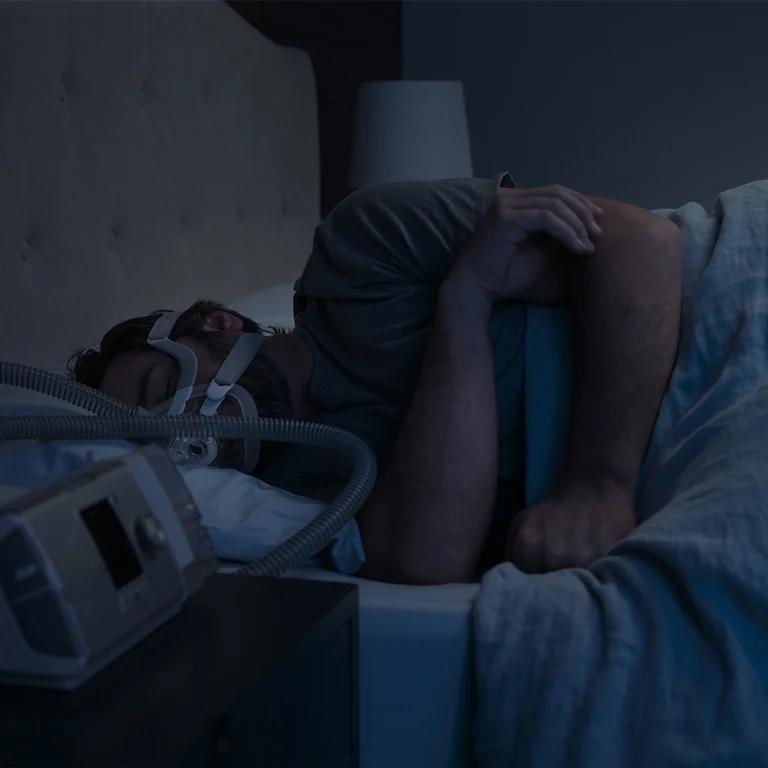 The image portrays a person sleeping with a CPAP (Continuous Positive Airway Pressure) machine.
