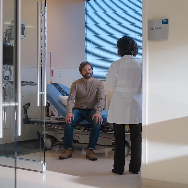 Image shows two people having a conversation in a medical facility.